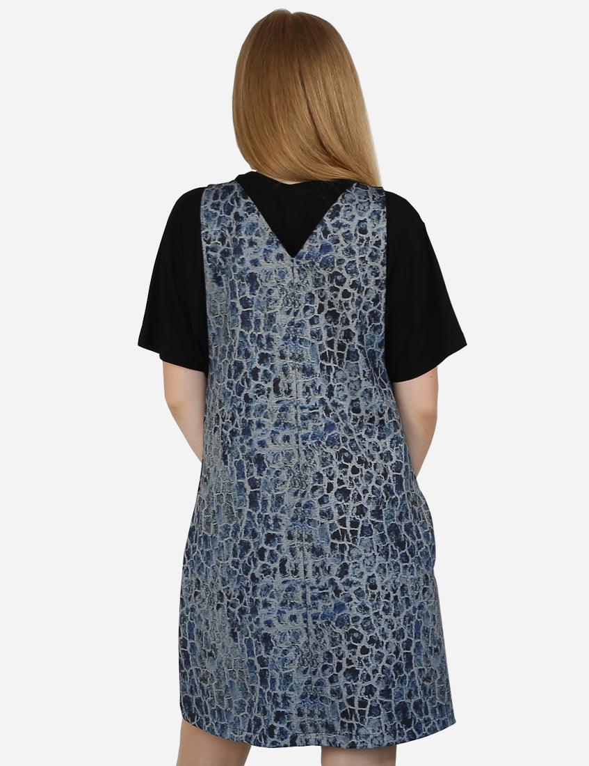 Back view of a woman in a blue patterned pinafore dress that creates a lively look, over a black t-shirt.