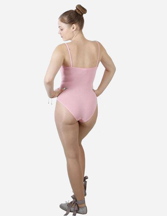 Back view of a dancer in a pink camisole leotard with ballet bun, standing with a white background