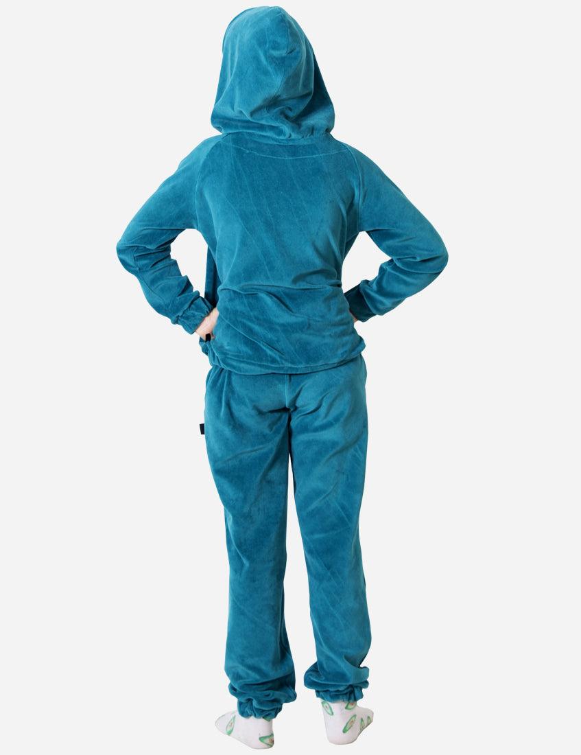 Rear view of a young girl wearing an electric blue velvet tracksuit, highlighting the hoodie and comfortable fit, paired with playful socks.