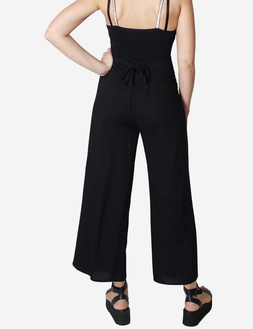 Back view of a woman wearing relaxed-fit black trousers with a matching top, highlighting the easy-wear design.
