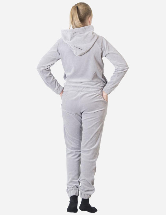 Back view of a woman wearing a plush grey velvet tracksuit, displaying the hood detail and the snug waistband of the pants for a cozy fit.