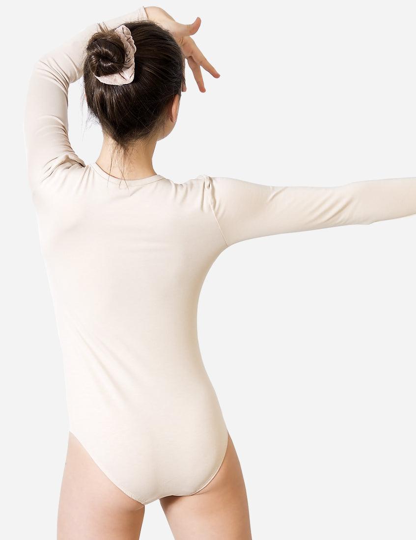 Back view of a young girl in a beige leotard with hair bun preparing for a ballet class