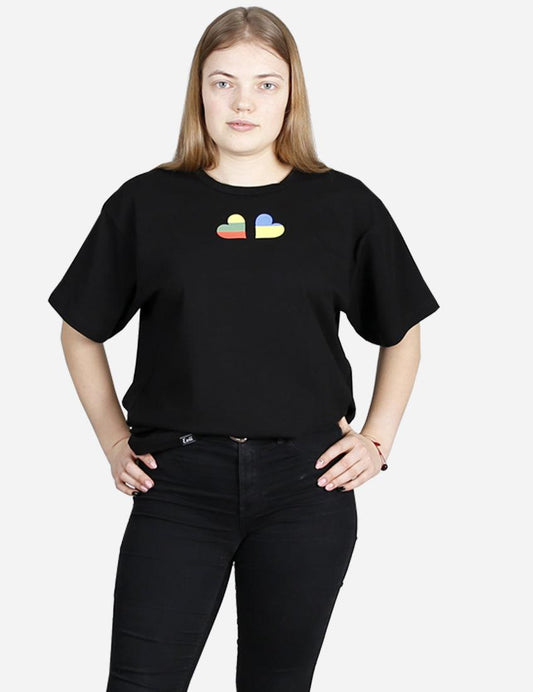 Front view of a young woman wearing a black crew neck t-shirt with a symbol of unity emblem to support Ukraina