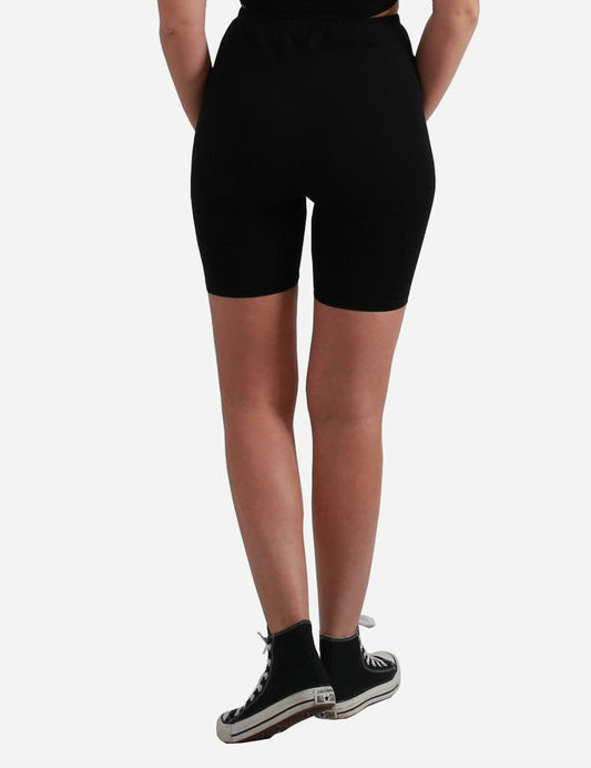 Rear view of black cycling shorts on a woman paired with classic high-top sneakers.