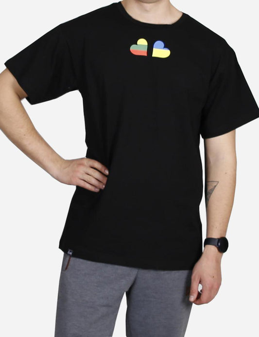 Man in black t-shirt with colorful dual-heart design standing with a confident posture to support Ukraina