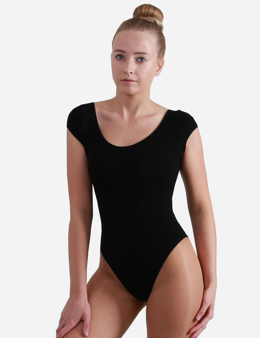 Front view of a woman in a chic black leotard with winged sleeves, posing with one leg forward and ballet flats on.