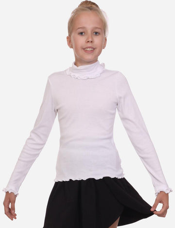 Young girl posing in a white long-sleeved turtleneck with delicate ruffle detailing at the collar and cuffs, paired with a black skirt.