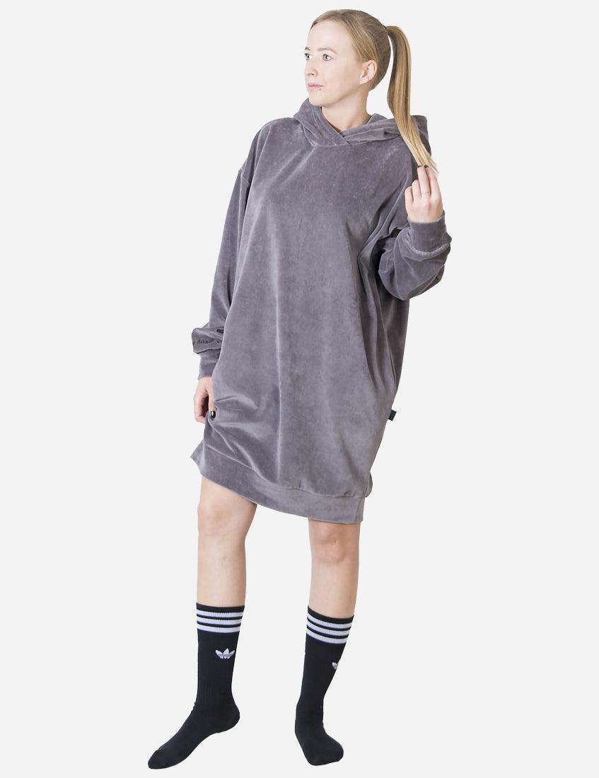 Confident woman in a soft velvet dress in a light grey color, complemented by sporty black socks with white stripes, offering a trendy, casual look.