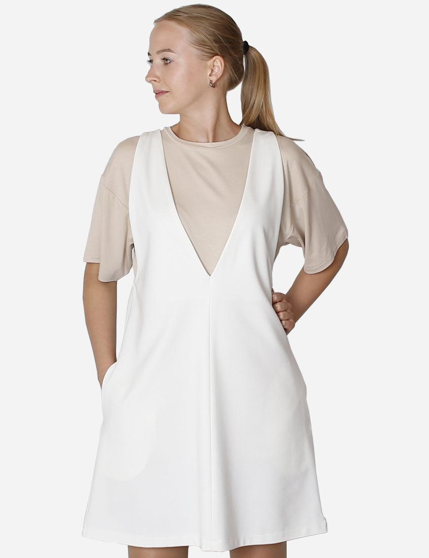 Elegant woman in a milk-colored pinafore dress with a beige undershirt, side profile view.