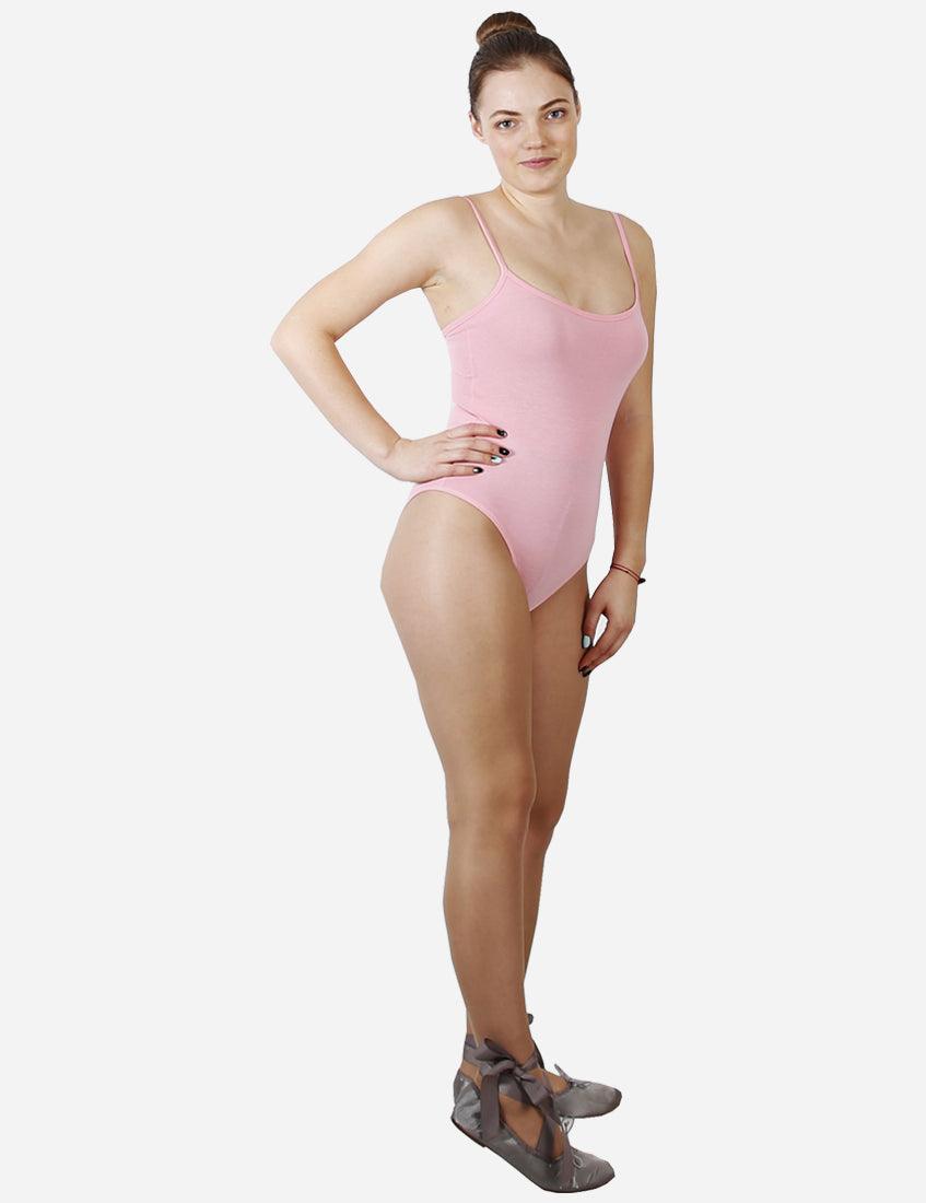 Female ballet dancer in a pink spaghetti strap leotard standing in profile on tiptoe with ballet shoes