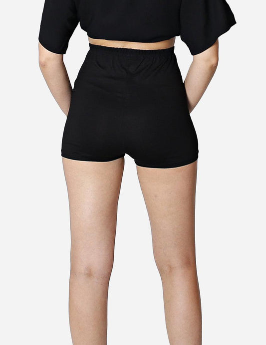 Close-up of high-waisted black yoga shorts on a woman with a neutral backdrop.