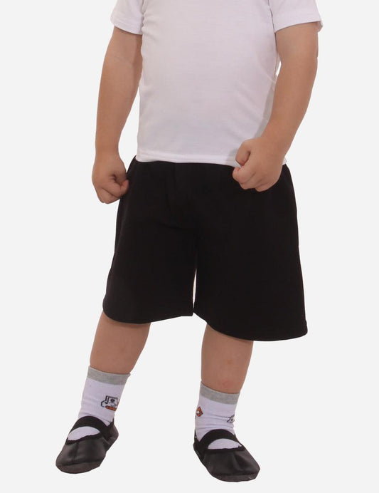 Little boy in white t-shirt and exclusive black shorts standing straight, wearing black ballet shoes and white socks with grey accents, isolated on white background.