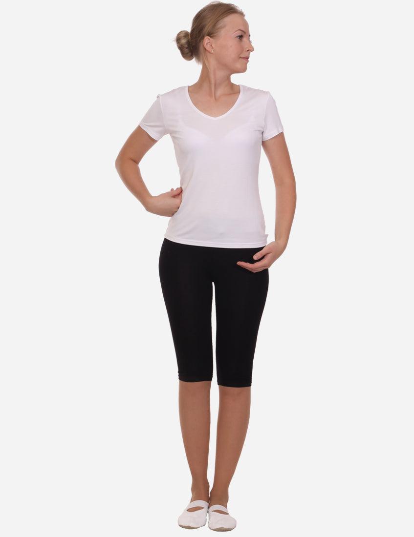 Side view of a woman in high-waisted black capri leggings with white t-shirt, casual style with white ballet flats, isolated on white background.