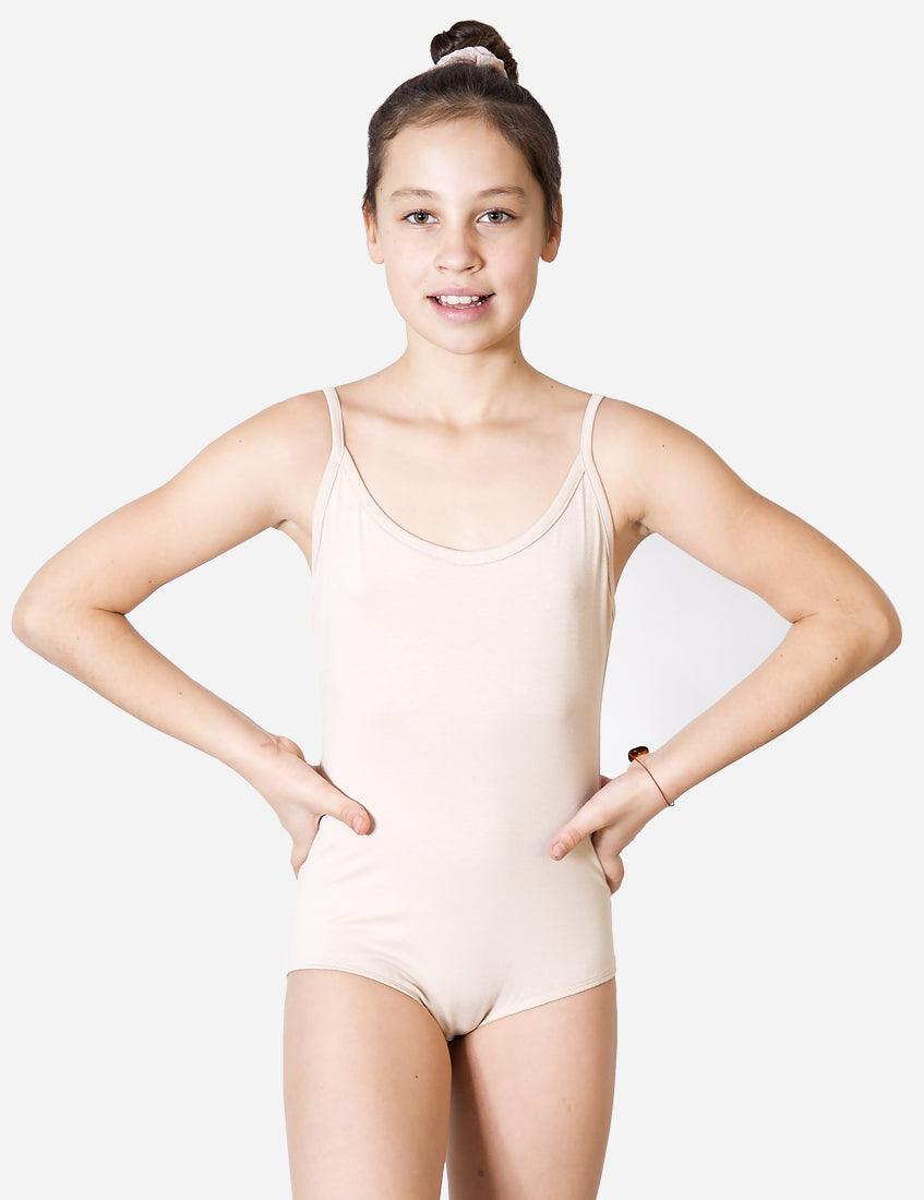 Smiling young ballet student in skin-tone tank leotard with ballet hair bun standing relaxed on white backdrop