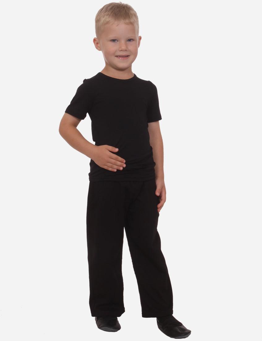 Smiling young boy in black t-shirt and pants standing against a white background, front view.