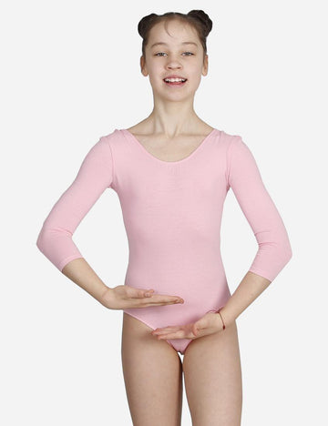 Smiling young dancer in pink leotard with three-quarter sleeves and white ballet flats