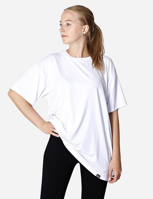 Woman standing with hand on hip wearing white oversized t-shirt, showing front design.