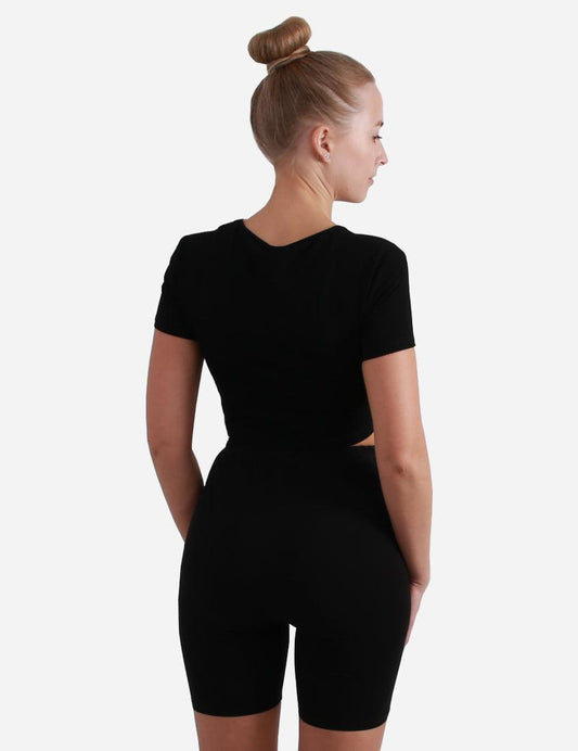 Back view of a woman in a black short sleeve cropped top on white background