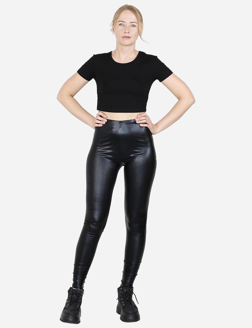 Woman showcasing black faux leather leggings with a cropped black top, front view, white background.
