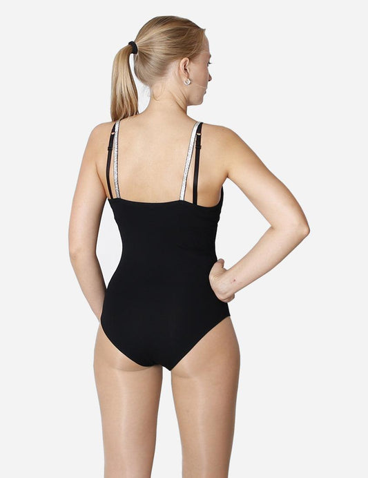 Woman in black leotard with glittery shoulder straps standing looking away on white background
