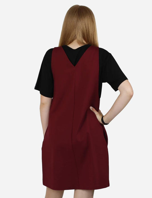 Rear view of a young woman wearing an elegant burgundy pinafore dress with a black T-shirt, highlighting the V-neck back cut.