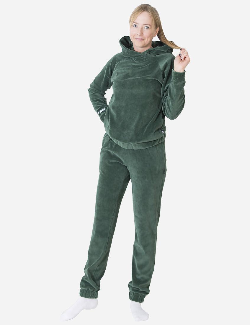 Woman smiling at the camera in a cozy green velvet tracksuit, full-length image capturing the comfortable design and texture of the suit.
