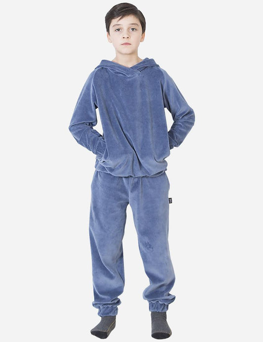 Young boy wearing a cozy blue velvet tracksuit with a hoodie, looking casual and comfortable, hands in pockets.