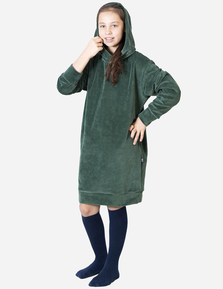Young girl posing with a smile in a warm dark green velvet dress, paired with navy blue knee-high socks for a cozy and stylish look.